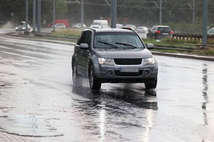 Auto sobre asfalto mojado ilustrando el riesgo de aquaplaning con lluvia